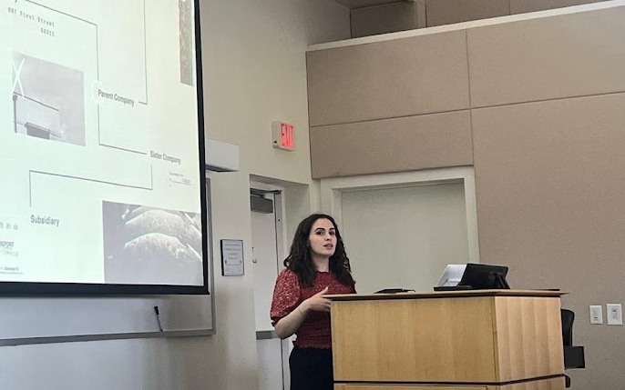 Gabby Carmine presenting research beside a projected slide.