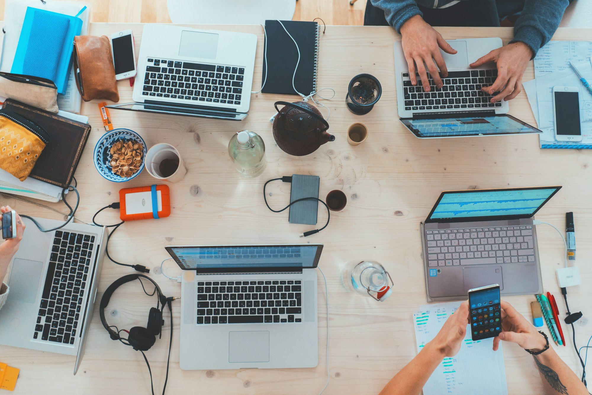 A collaborative table with laptops, notebooks, and coffee during a work session.
