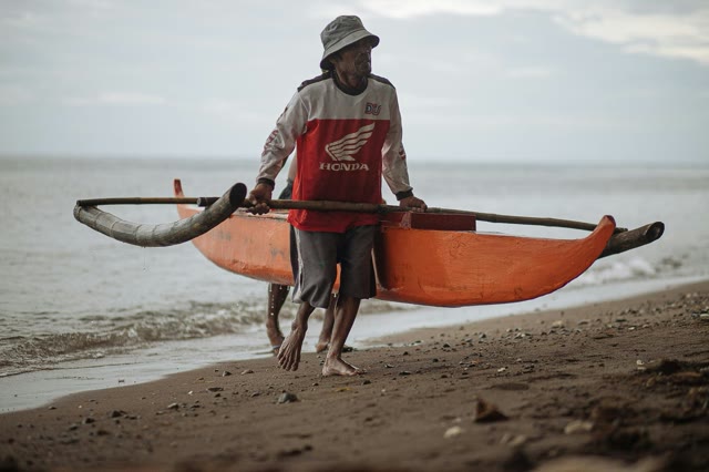 Traditional fisher pulling a canoe ashore